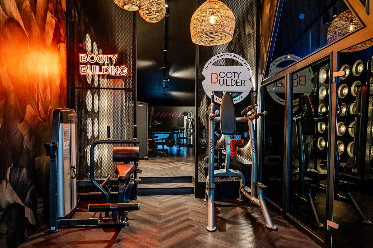 Stilvoller Booty Builder Bereich mit Rattan-Lampen und Fischgrät-Boden im GymOne 24/7 Bitburg