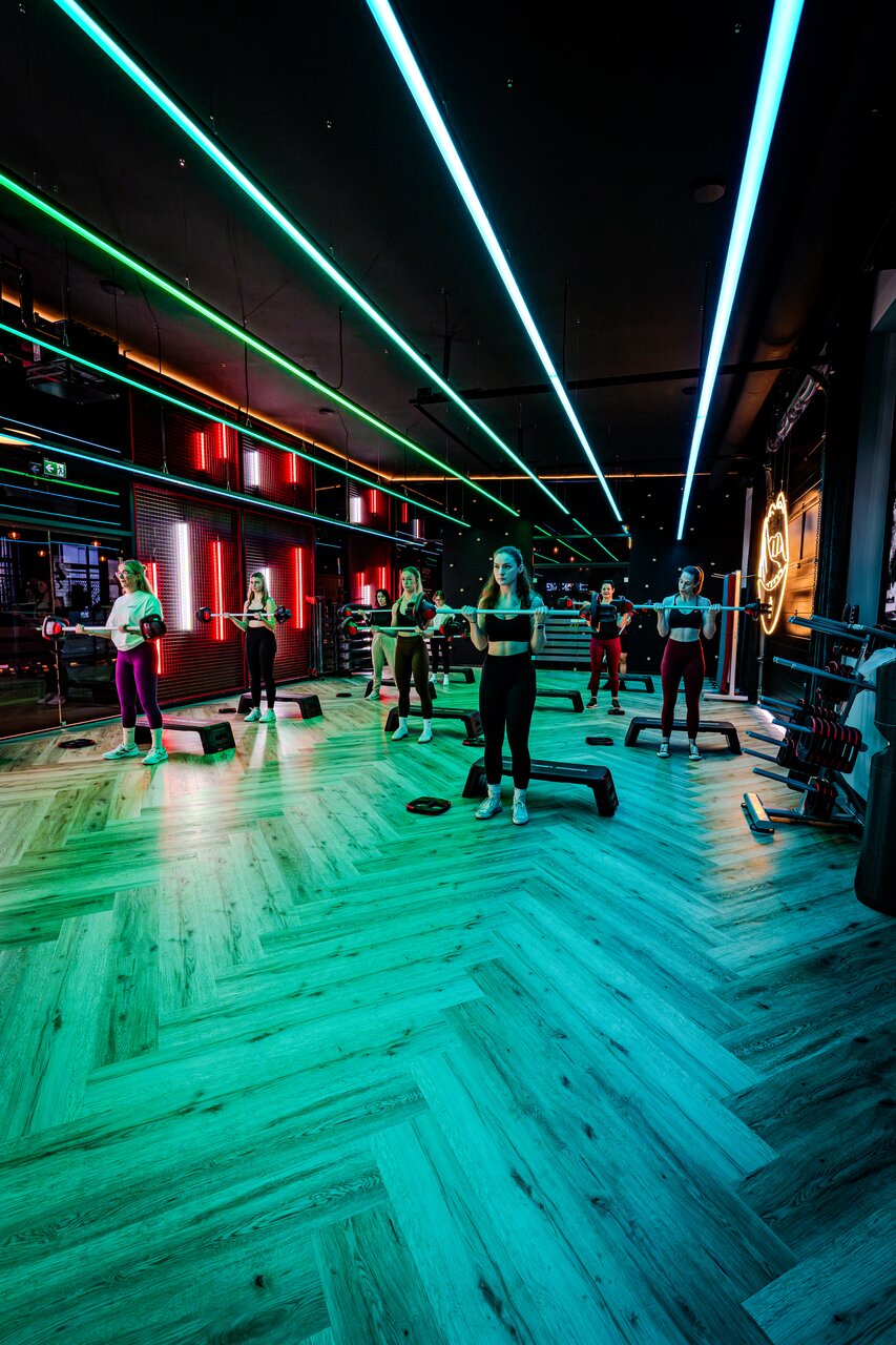 Les Mills Gruppenkurs mit Langhantel-Training im Fitnessstudio Bitburg GymOne 24/7 mit stimmungsvoller LED-Beleuchtung